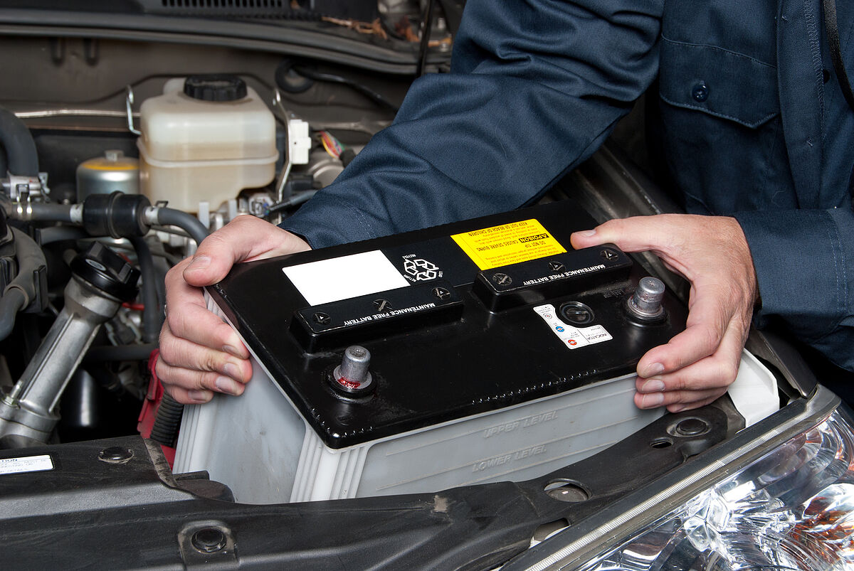 Jahreszeiten-Check-Up A car mechanic replaces a battery.